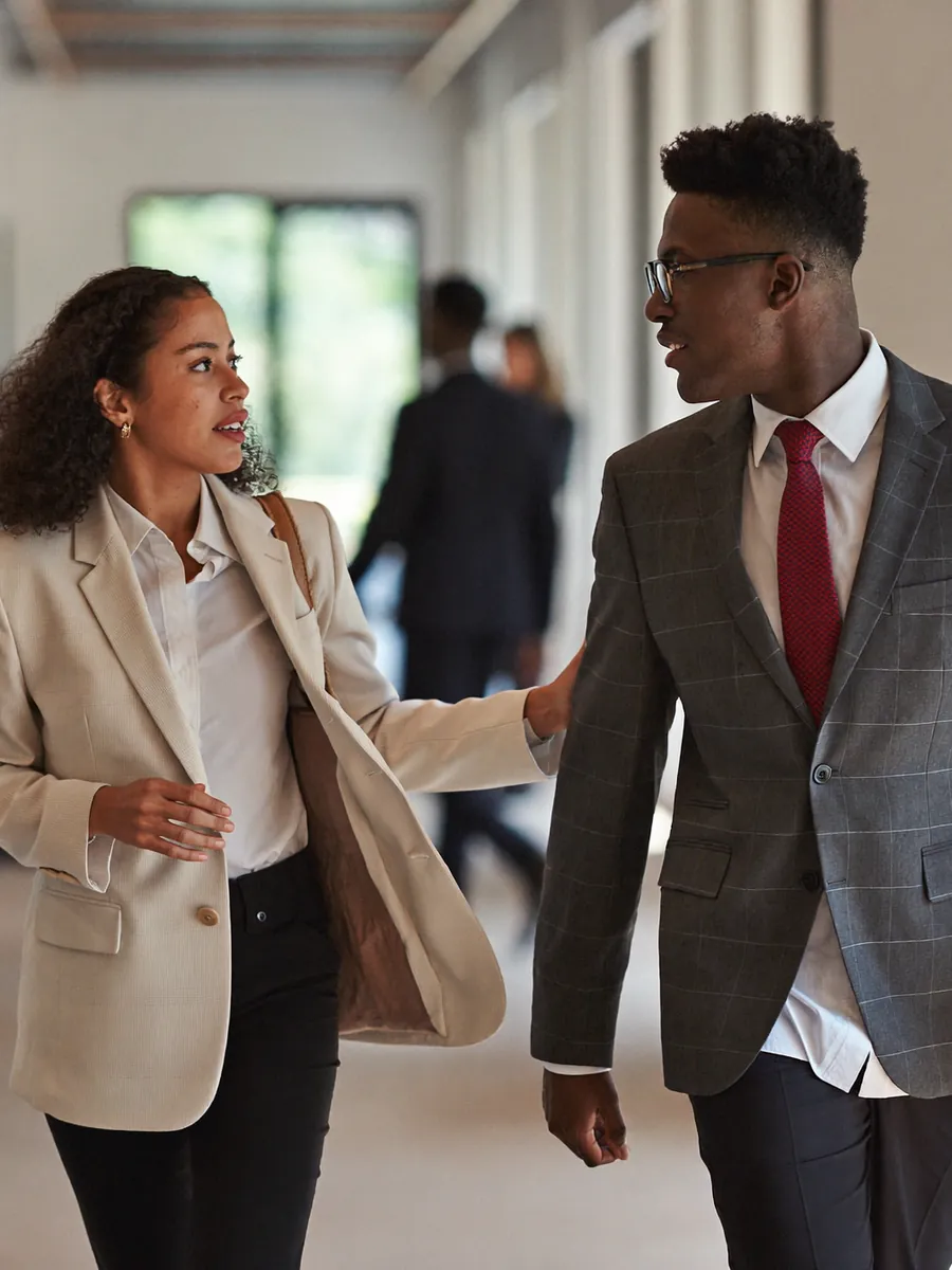 Two colleagues walking and talking in a bright office corridor