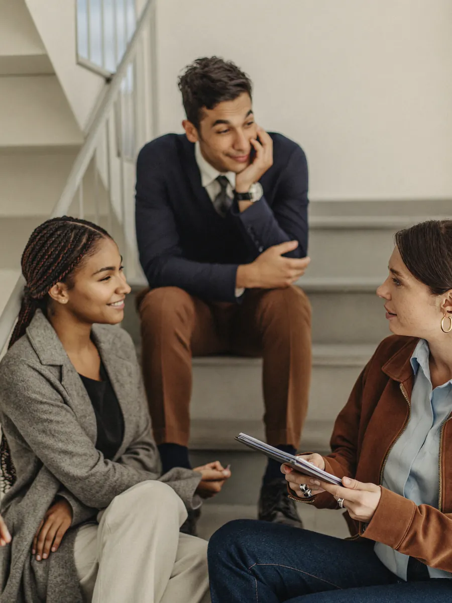 Four professionals debriefing informally on a bright stairwell landing