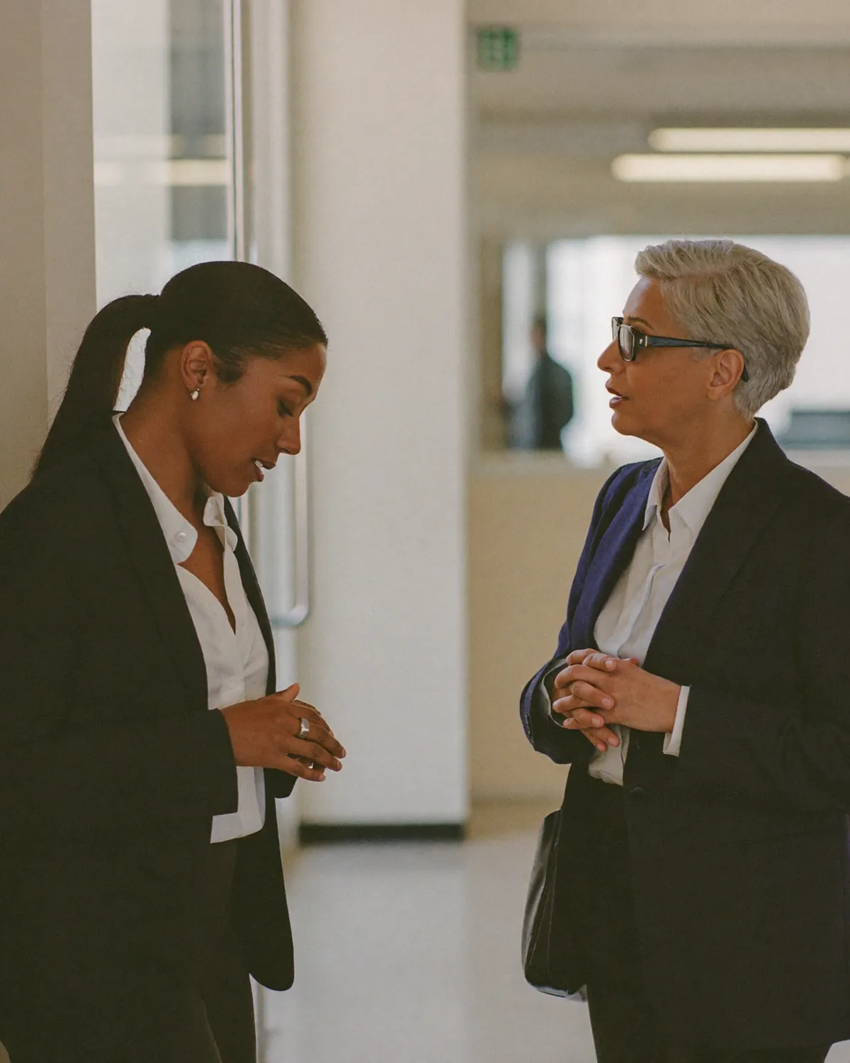 Two colleagues talking one-to-one at the edge of a bright conference foyer