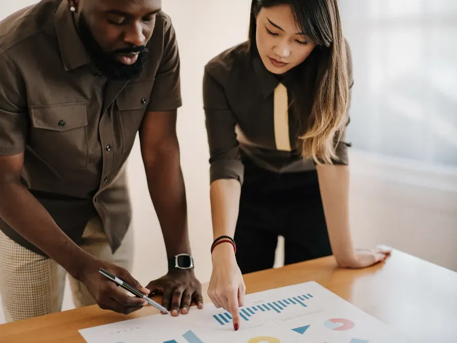 Two colleagues reviewing a printed chart together at a standing desk