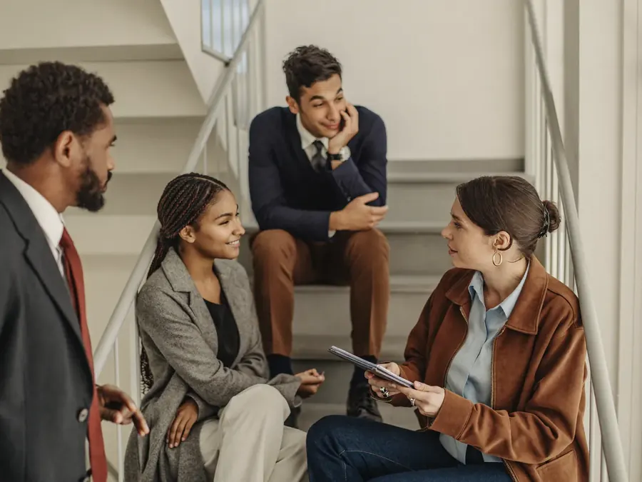 Four professionals debriefing informally on a bright stairwell landing