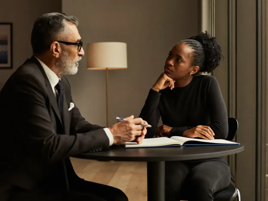 An executive coaching conversation between two professionals beside a window