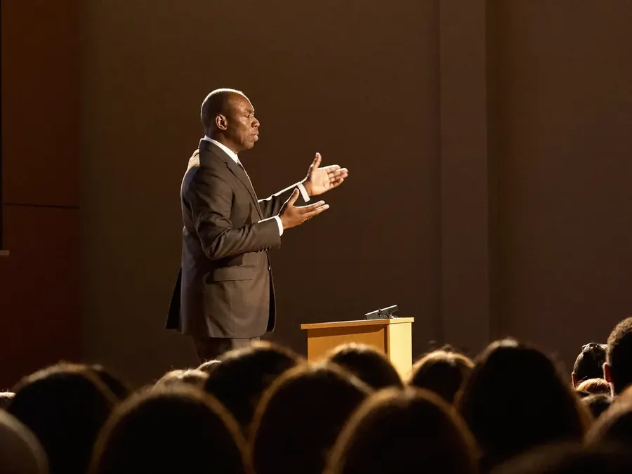 A speaker delivering a keynote on stage in front of a large audience